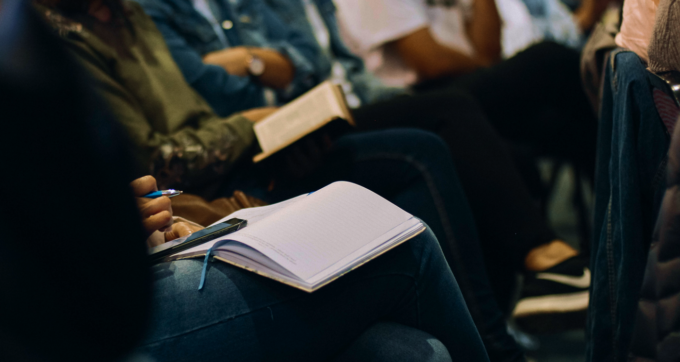 People sitting in a lecture holding a notebook and pen