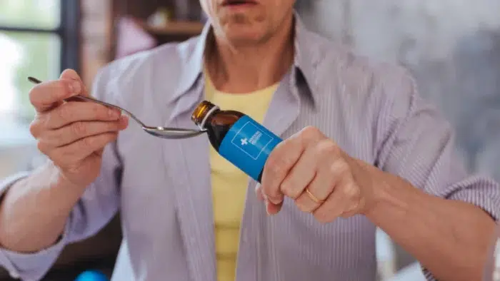 Man pouring medicine into a spoon