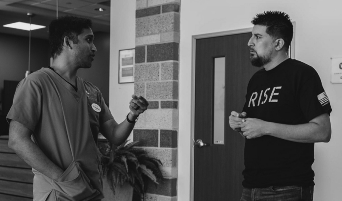 Two men engaged in conversation at a clinic hallway